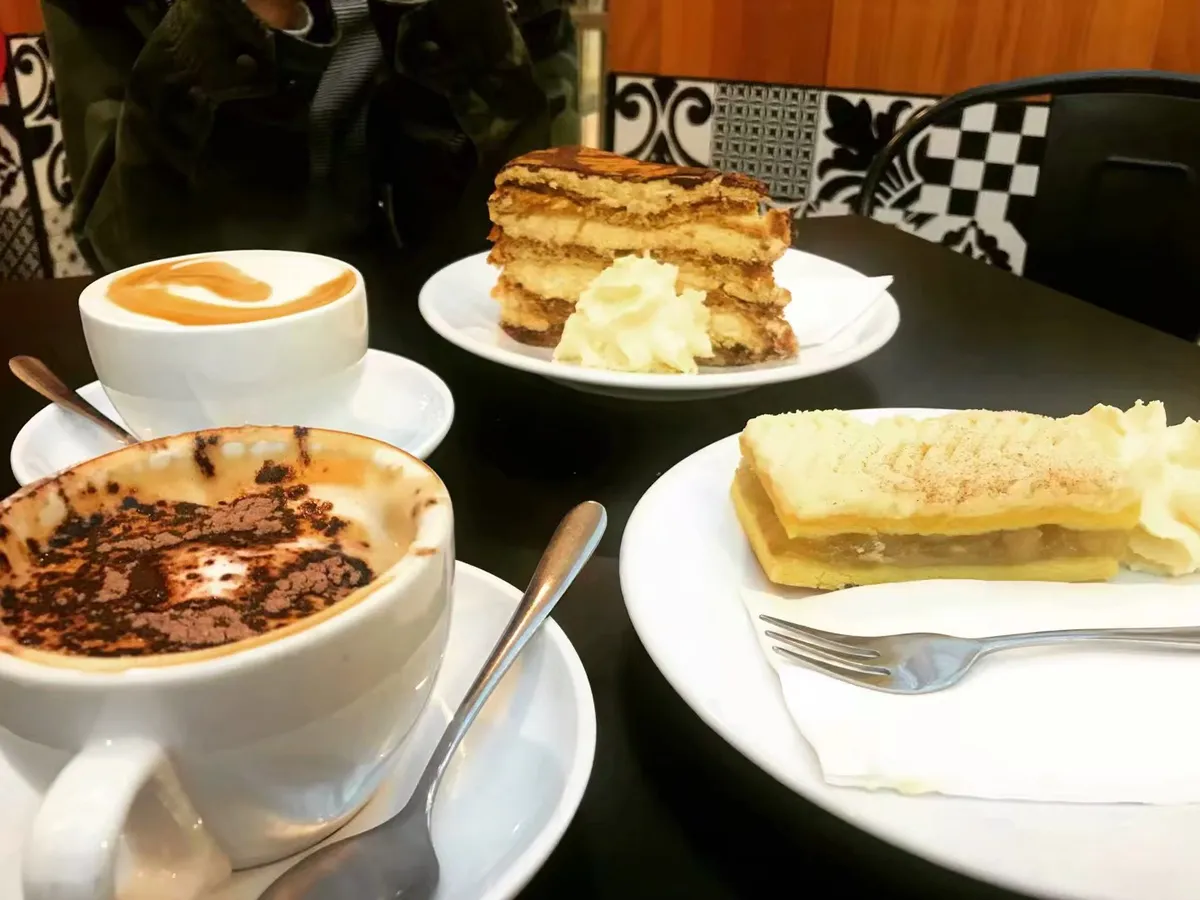 Cake slices and cappuccinos on a cafe table