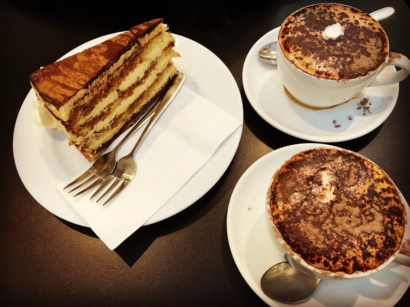 Tiramisu and two cappuccinos on a table at Elly Cafe